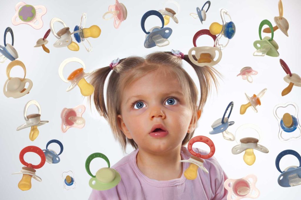 Toddler Girl surrounded by dropping pacifiers